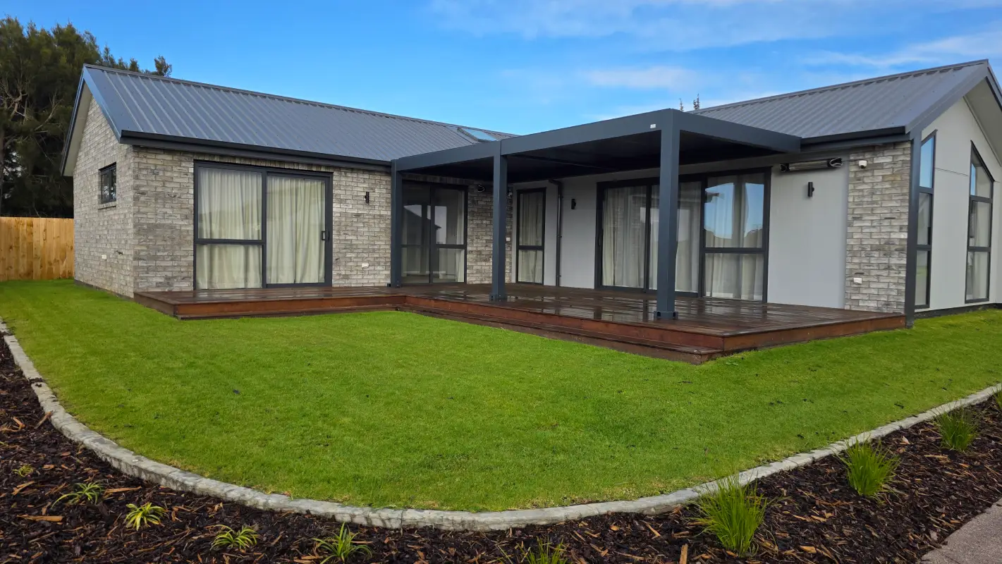k-turf-lawn-unwind-house-deck A modern Northland home with a covered timber deck, framed by a freshly laid green kikuyu lawn and a stone garden border